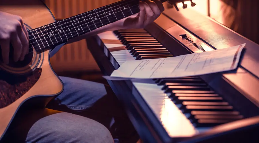 Guitar and piano with sheet music in a warm creative setting