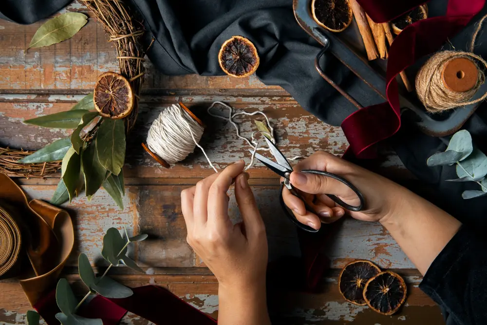 Hands cutting twine and assembling a seasonal wreath