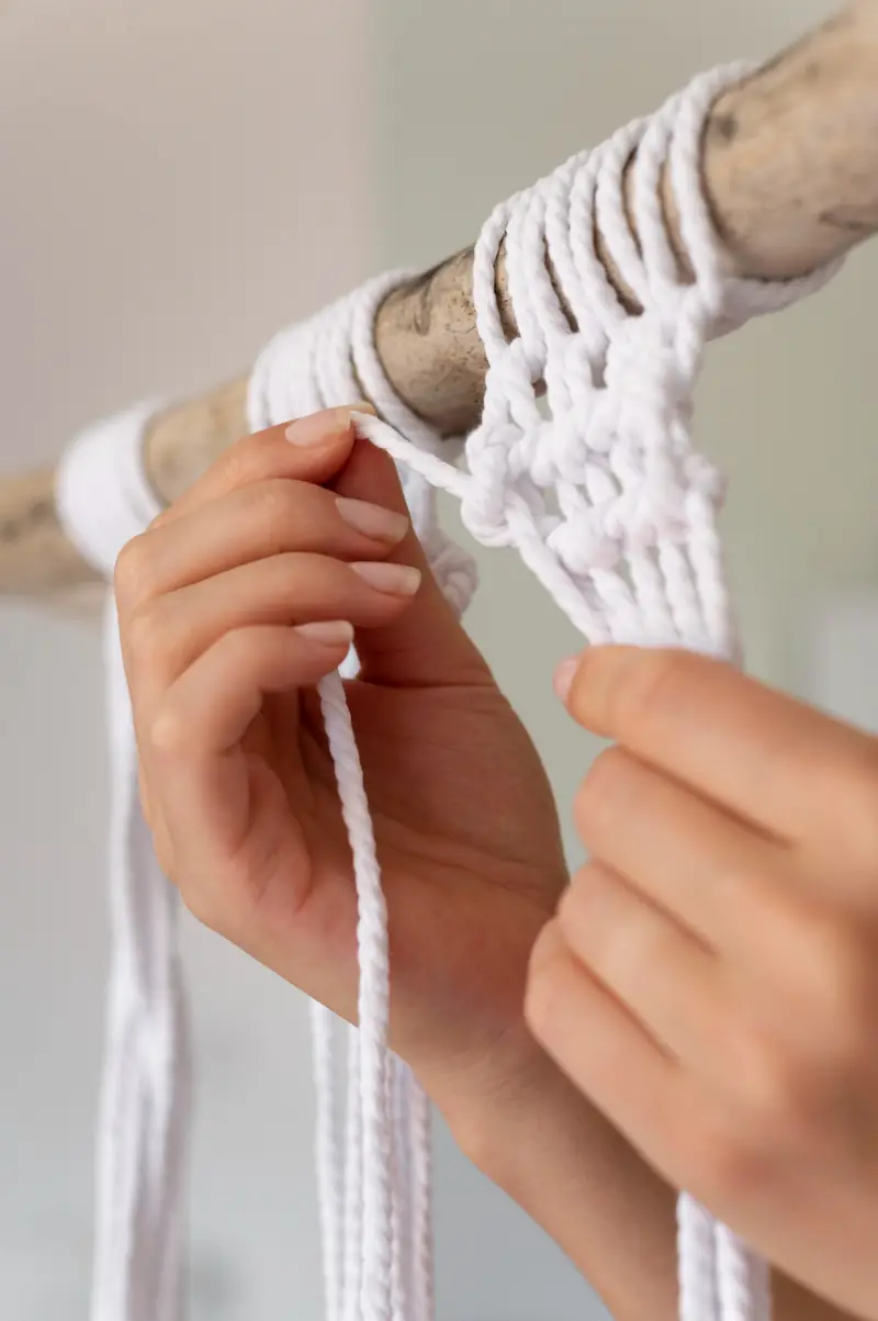 Hands using macramé technique with white cord